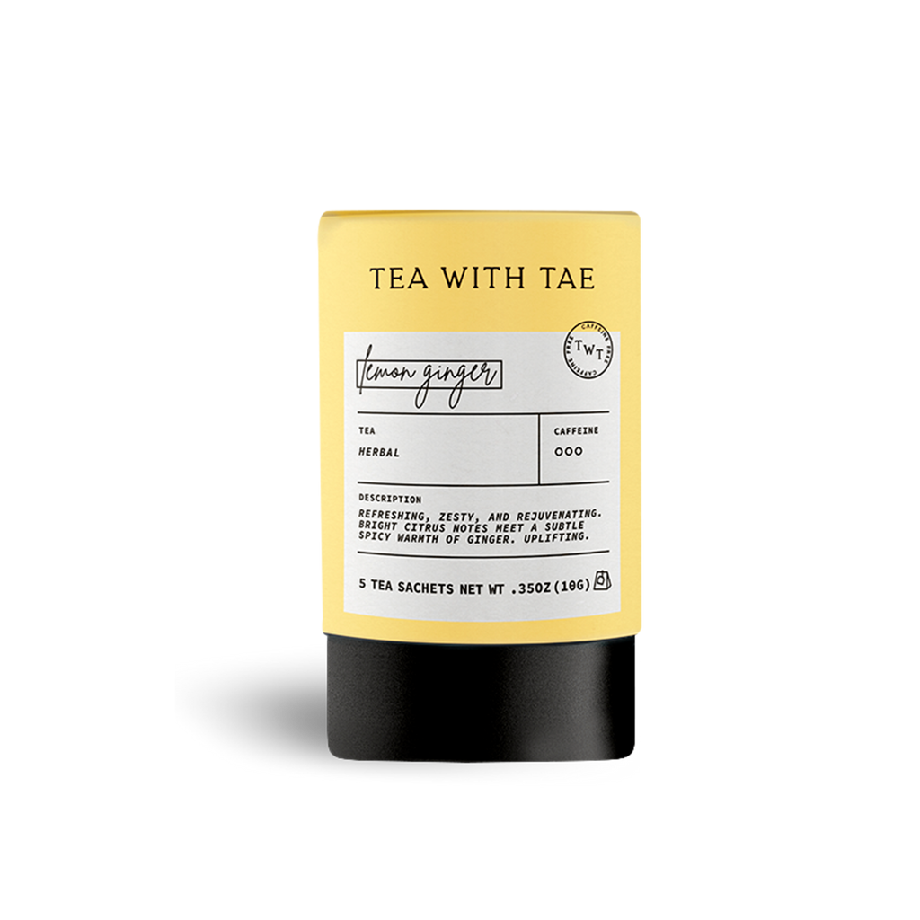 Yellow cylindrical tea packaging labeled 'TEA WITH TAE' and 'lemon ginger', with text describing 'Herbal' tea as 'refreshing, zesty, and rejuvenating. Bright citrus notes meet a subtle spicy warmth of ginger', on a white background.