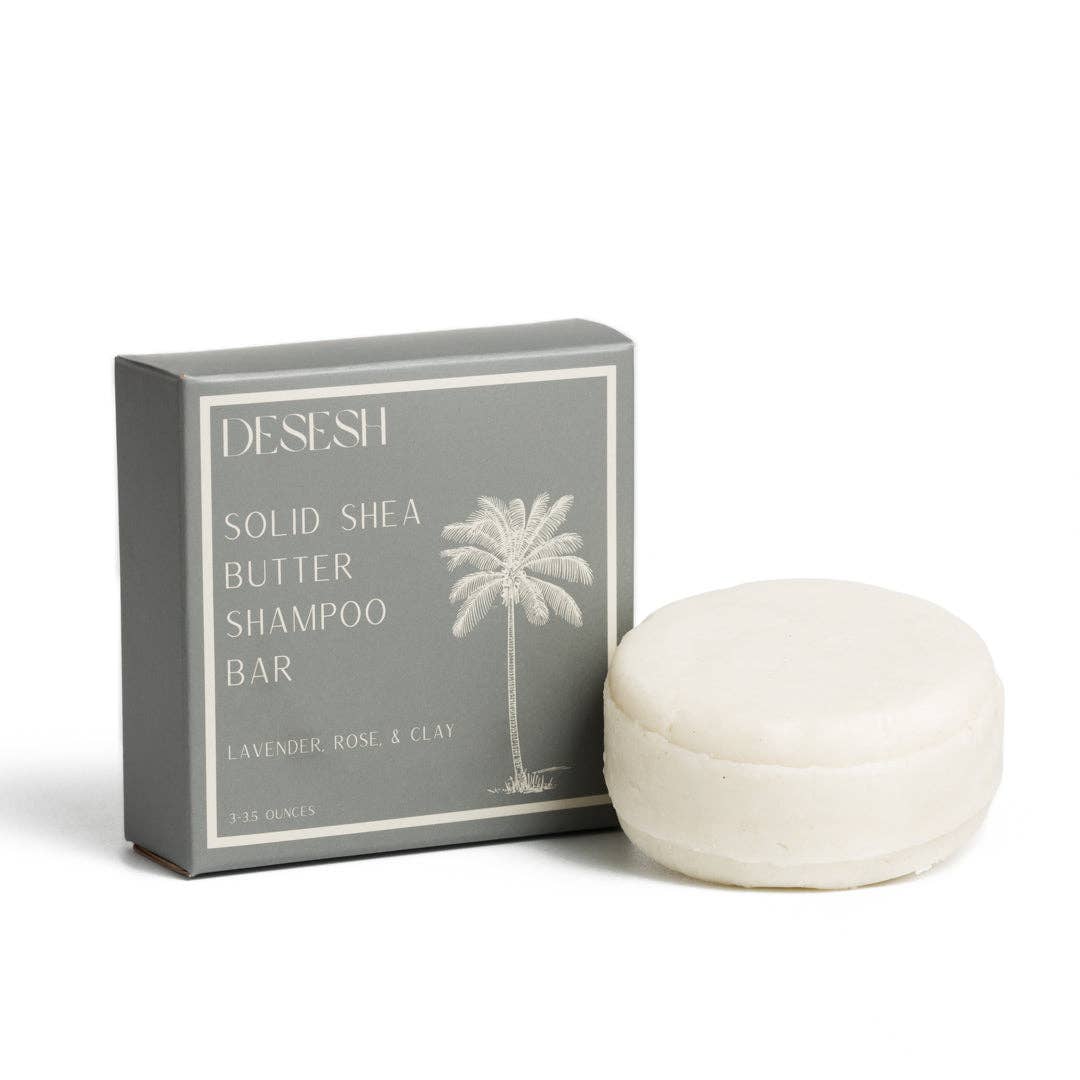 Gray box labeled 'DESESH SOLID SHEA BUTTER SHAMPOO BAR LAVENDER ROSE & CLAY' with a palm tree illustration, next to a round, white solid shea butter shampoo bar on a white background.