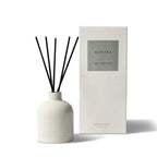 White ceramic diffuser bottle with black reeds, labeled 'MANTRA' and 'SWEET TANGY EXOTIC', next to a white box labeled 'MANTRA' and 'REED DIFFUSER'.