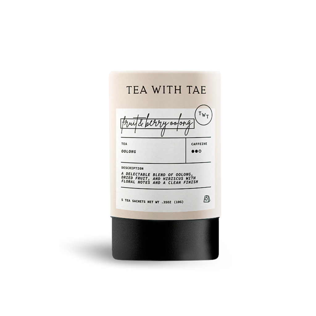 Light beige cylindrical tea packaging labeled 'TEA WITH TAE' and 'fruit & berry oolong', with text describing 'Oolong' tea as 'a delectable blend of oolongs, berries, fruit, and hibiscus with floral notes and a clean finish', on a white background.